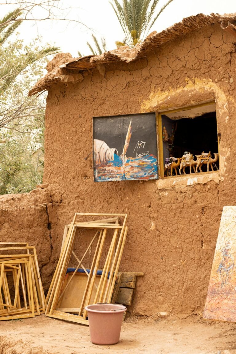 A charming clay cottage displays art and sculptures in a rural setting under daylight.