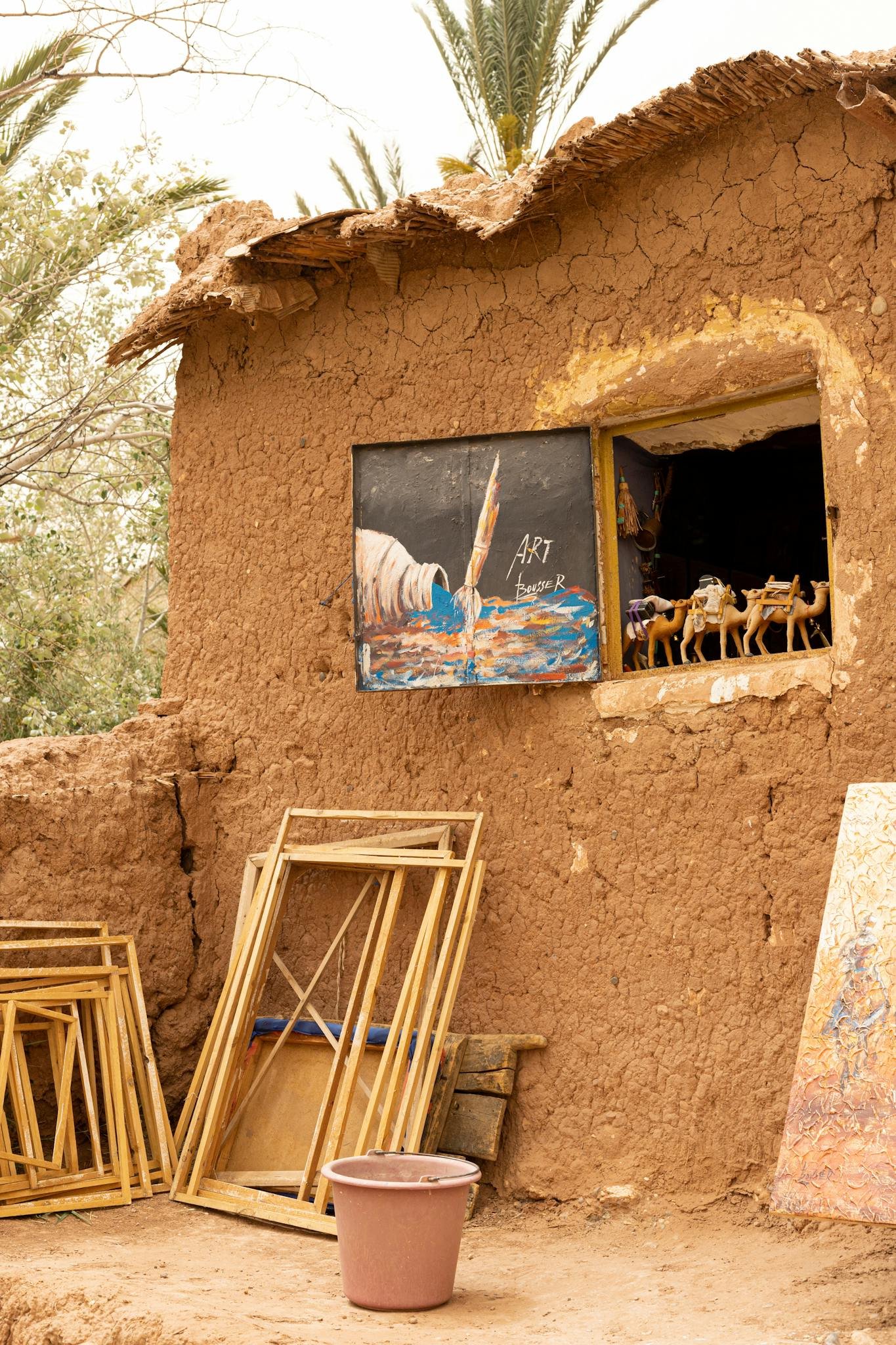 A charming clay cottage displays art and sculptures in a rural setting under daylight.